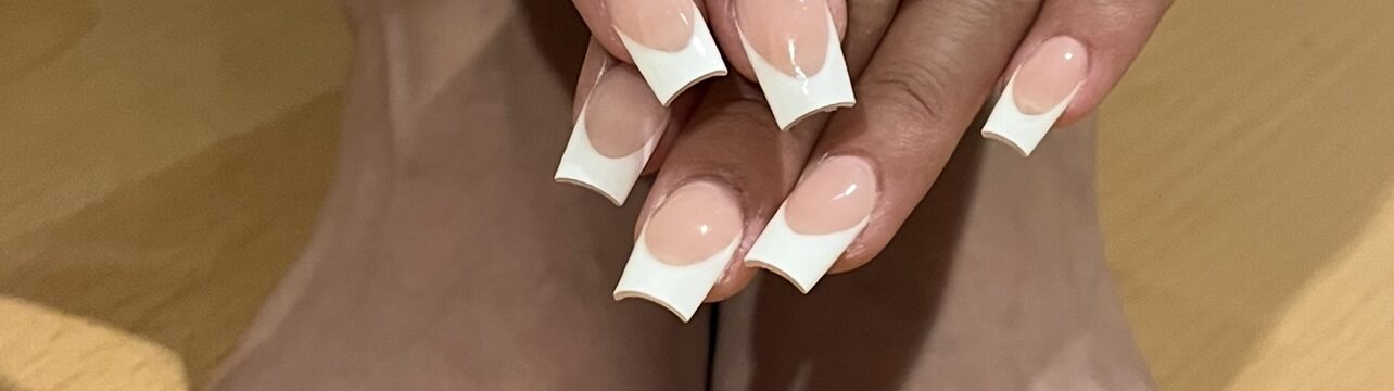 Close-up of elegant French tip nails paired with a smooth, vibrant single color pedicure, showcasing a polished and sophisticated look