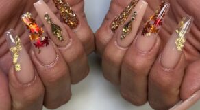 Autumn-themed nails with gold glitter, leaf designs, and jewel accents on a nude base. Perfect fall nail look created at NAB Nail Bar in Las Vegas.