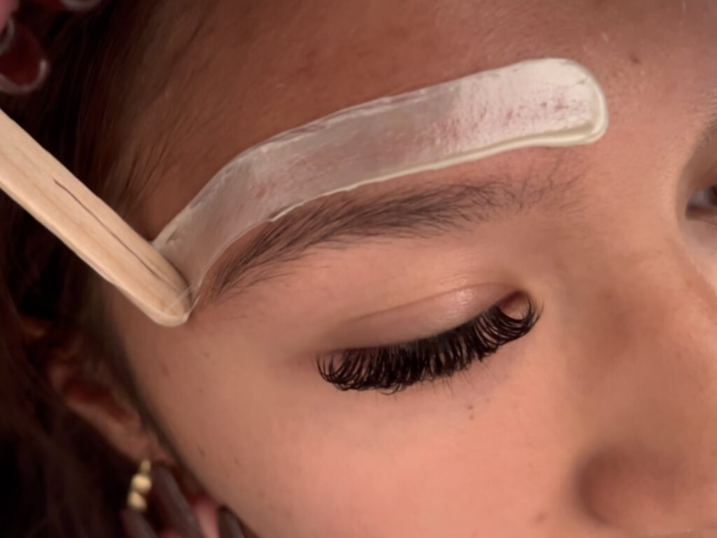 Close-up of brow waxing service by top nail technician, showcasing clean and well-shaped eyebrows